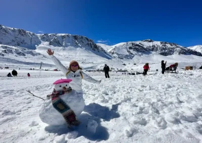 Turista haciendo un muñeco de nieve en Farellones. Actividad ideal para no esquiadores