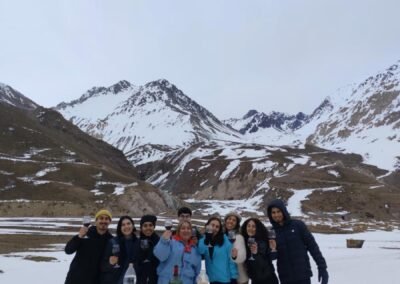 Grupo de turistas disfrutando de un picnic con vino y aperitivos en el Cajón del Maipo cubierto de nieve.