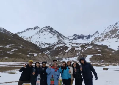 Grupo de turistas disfrutando de un picnic con vino y aperitivos en el Cajón del Maipo cubierto de nieve.
