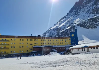 Fachada del icónico Hotel Portillo amarillo contrastando con la nieve y el cielo azul en el centro de ski.