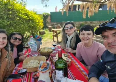 Grupo de amigos felices disfrutando un picnic con vino y snacks en el Tour Portillo y Laguna del Inca.
