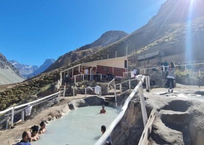 Turistas disfrutando de las piscinas termales y el paisaje cordillerano en las Termas de Colina, Cajón del Maipo, Chile.