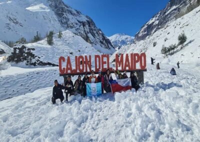 Grupo de turistas posando en el letrero de bienvenida al Cajón del Maipo nevado.