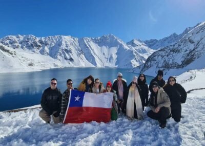 Grupo de turistas descansando en las rocas junto a la laguna turquesa del Embalse El Yeso