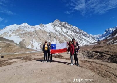 Grupo de turistas del tour posando felices en el Embalse El Yeso con parches de nieve.
