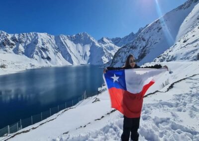 Persona de espaldas con brazos abiertos contemplando la inmensidad de la laguna turquesa del Embalse El Yeso.