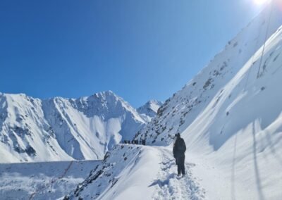 Dos personas caminando sobre la nieve en el Embalse El Yeso durante el tour de invierno.