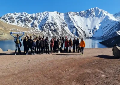 Grupo de turistas disfrutando el tour Embalse El Yeso frente al lago turquesa y montañas nevadas.